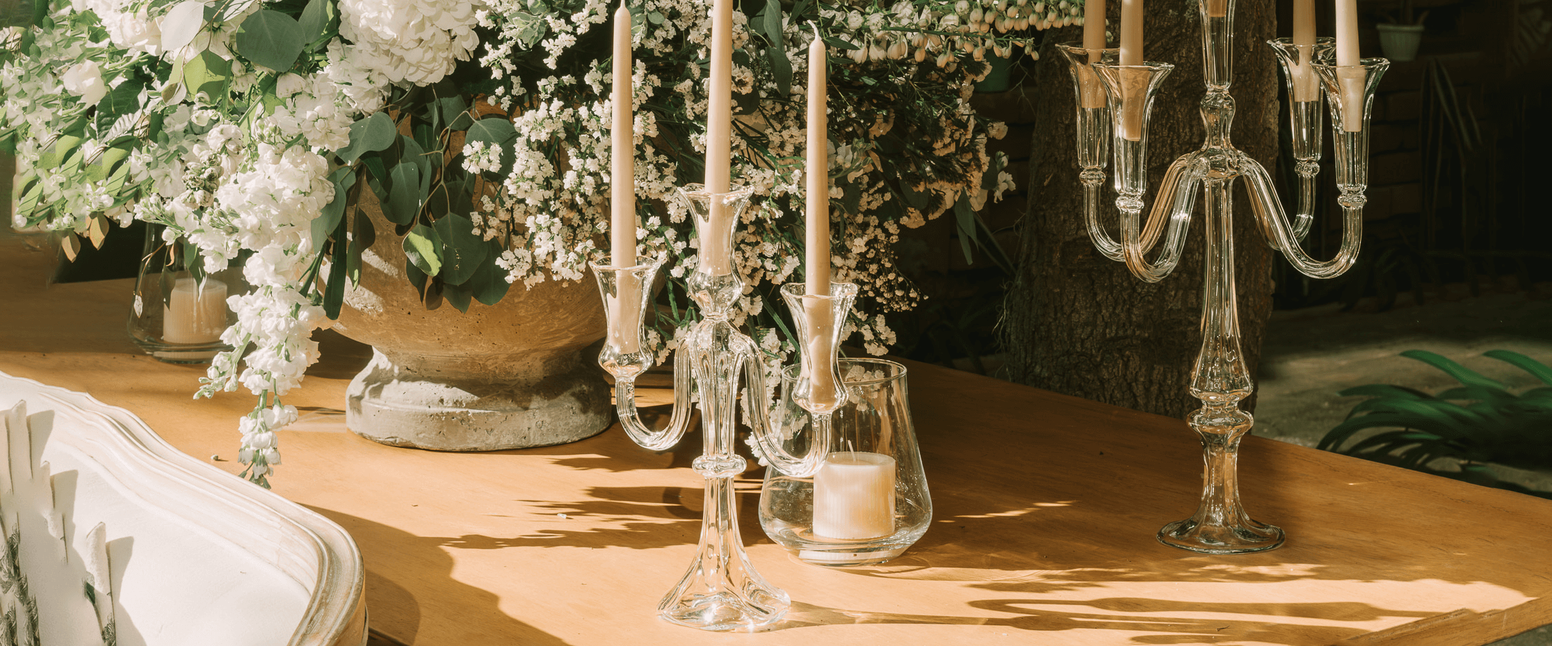Hand-blown glass candelabras by Gabriela Seres on a garden table, candlelight reflecting beside lush white florals.