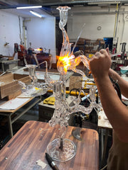 Clear glass candelabra being worked on in a workshop setting