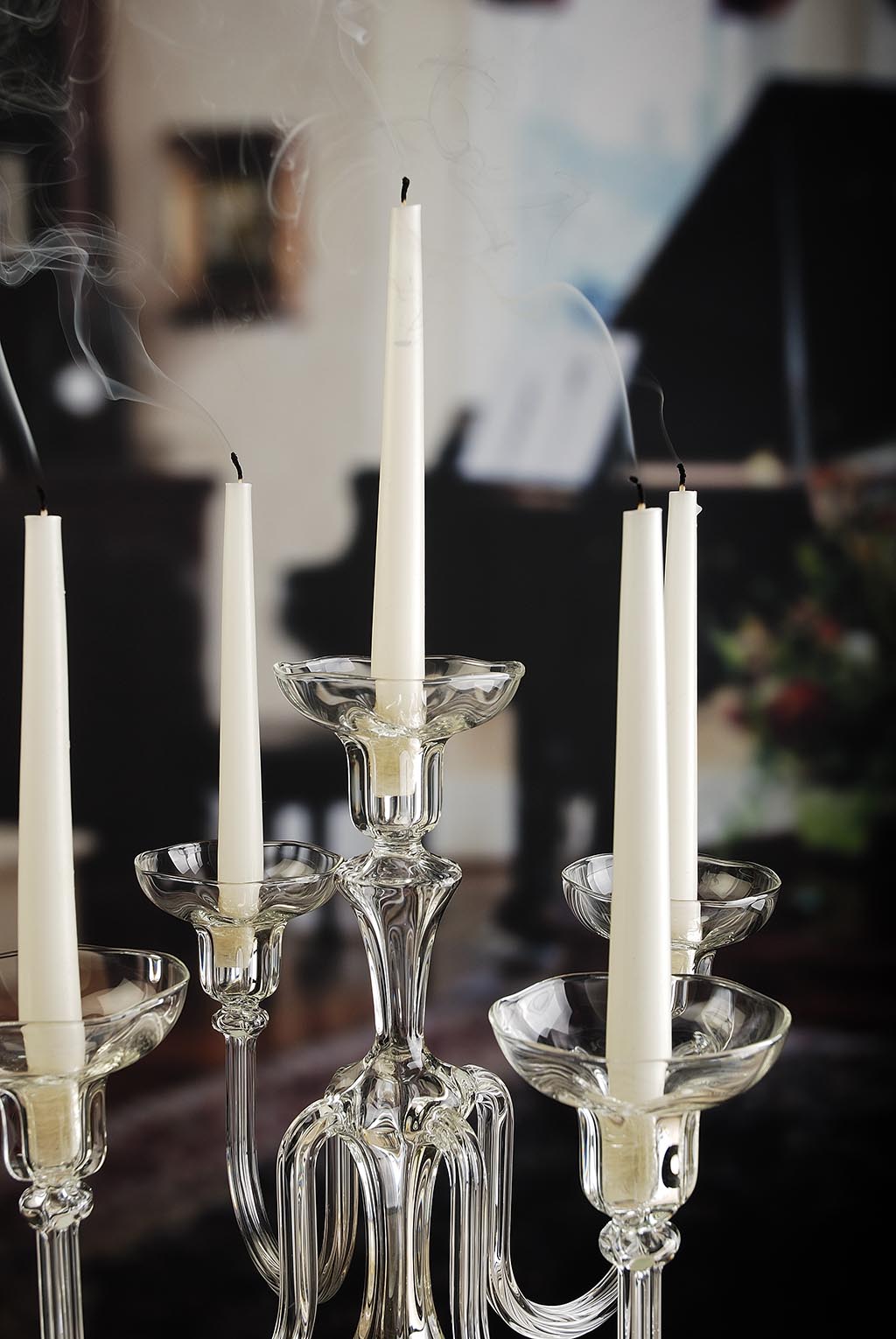 Clear glass candelabra with white candles in a blurred indoor setting