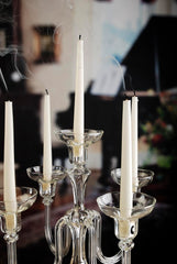 Clear glass candelabra with white candles in a blurred indoor setting