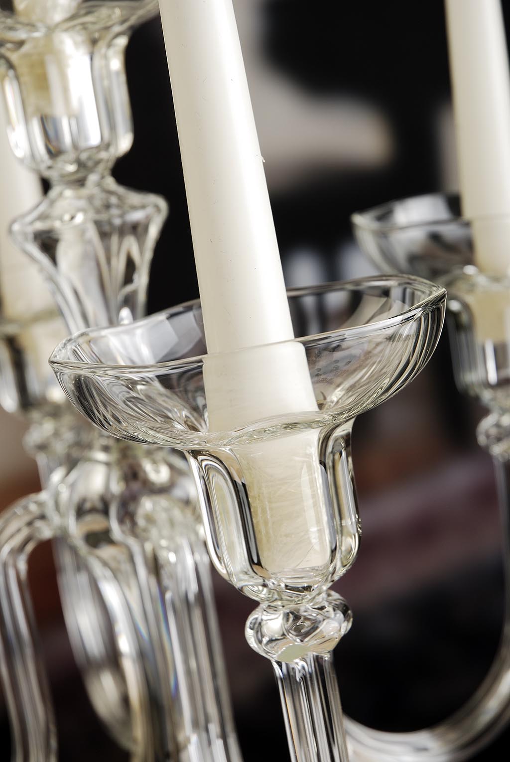 Close-up of a chandelier with clear glass candle holders and white candles.