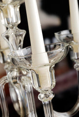 Close-up of a chandelier with clear glass candle holders and white candles.