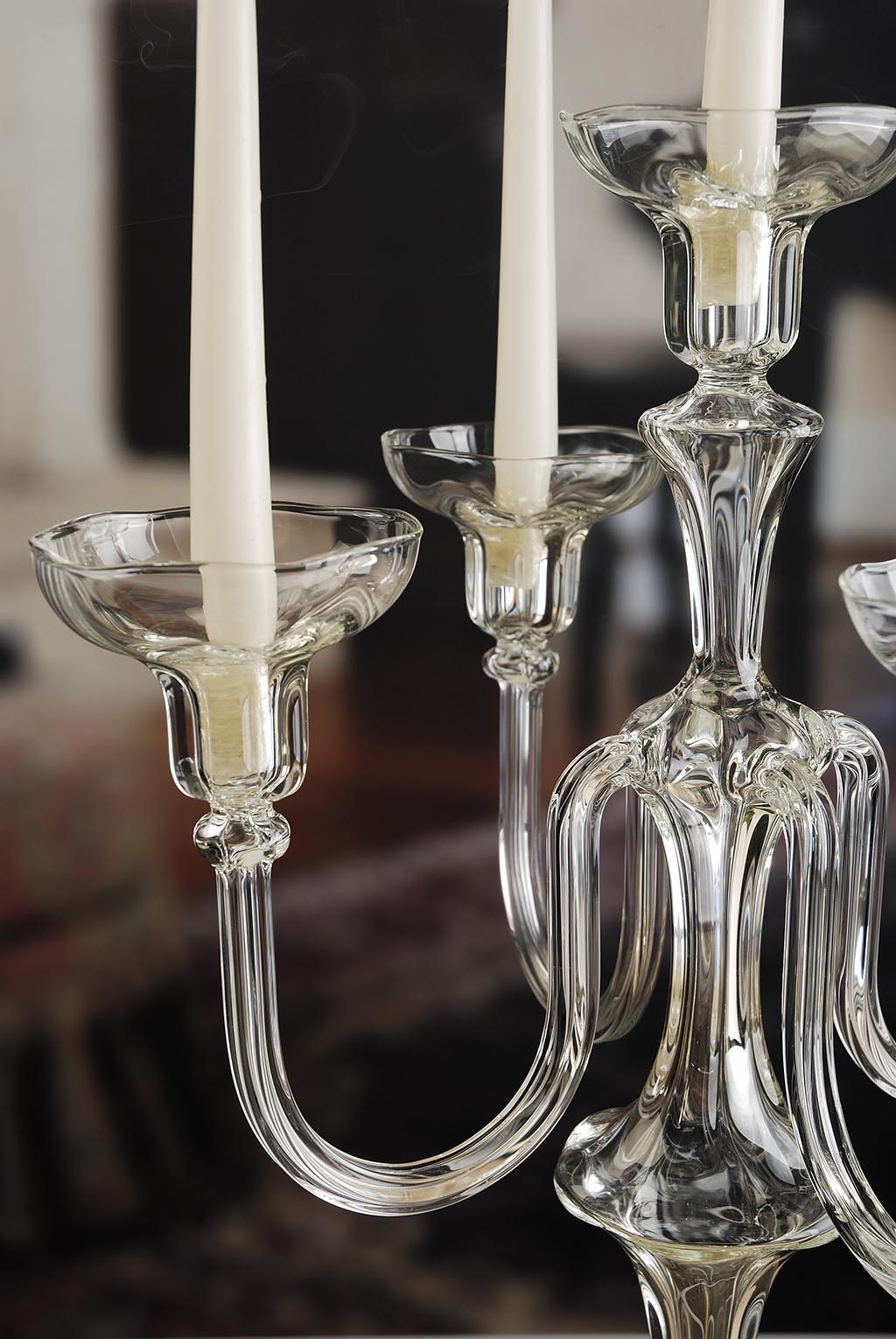 Close-up of a glass candle holder with three candles against a blurred background